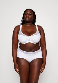 Conjunto de lingerie branca com soutien com detalhes em tule e cueca combinando. O tecido é suave, oferecendo um design básico e minimalista.