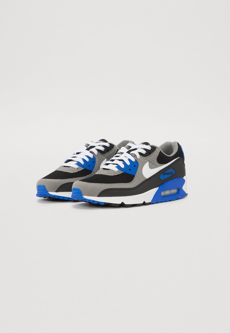 Nike Air Max 90 to sneakers z czarno-szarym siateczkowym wierzchem z niebieskimi akcentami, białymi sznurówkami i białą podeszwą pośrodkową. Teksturowana gumowa podeszwa.