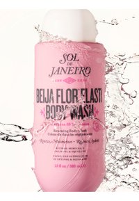 Bouteille rose Pink Sol de Janeiro Beija Flor Elasti Body Wash avec de l'eau éclaboussant autour sur un fond blanc.