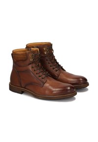 Botas de tobillo de cuero marrón con un acabado suave, diseño de cordones y acentos en color beige en el cuello, que presentan costuras decorativas y suelas de goma.