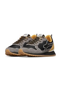 Un paio di sneaker nere, grigie e giallo senape con lacci a fantasia e suole in gomma testurizzata, posizionate affiancate su uno sfondo bianco.