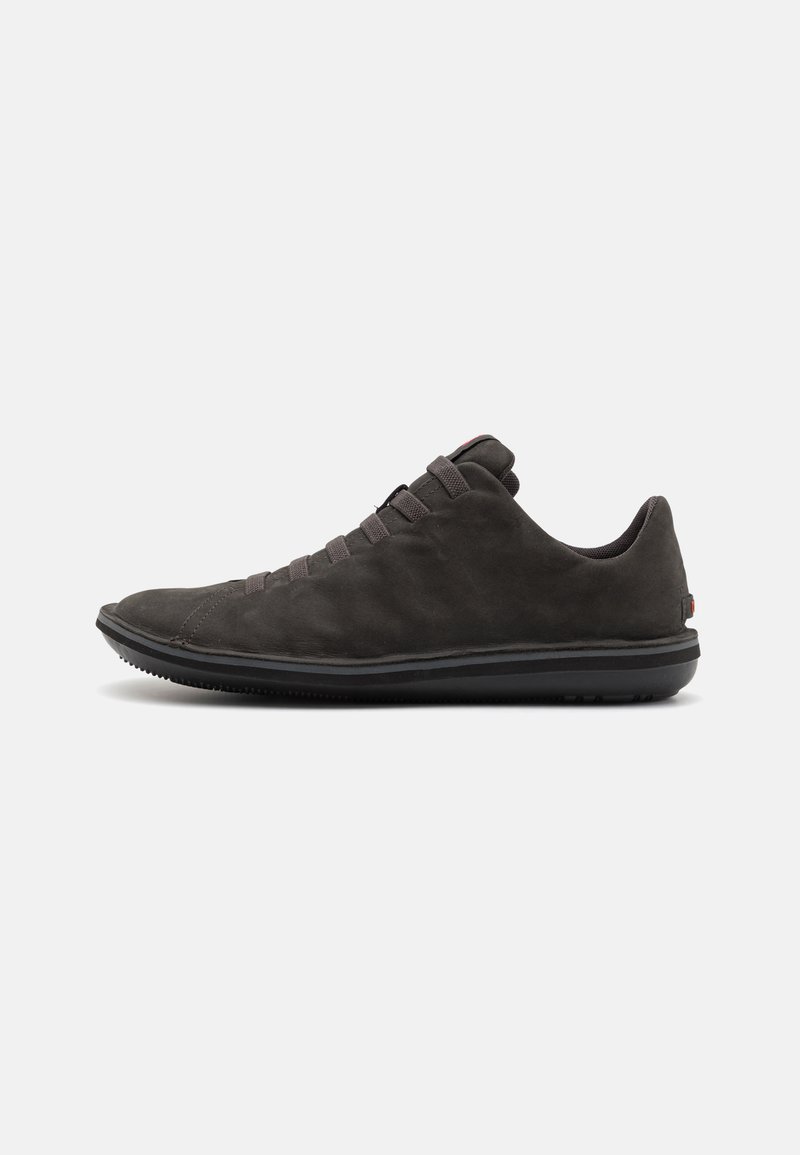 Tumehall suedesneaker madala profiiliga, millel on elastsed paelad, ümar varvas ja kareda musta kummist välistald.