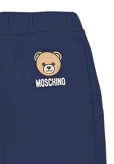 Marineblauwe sweatpants met ribbelstructuur, voorzien van een tan kleurige berenafbeelding en "Moschino" tekst in het wit. Elastische tailleband voor extra comfort.
