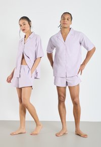 Lavender short-sleeve button-up shirt with a chest pocket, paired with matching shorts. Soft, lightweight fabric with a smooth texture.