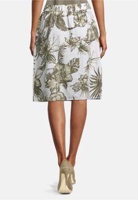 Polvepituinen hame, jossa on valkoinen tausta ja vihreitä kukkakuvioita, joustava vyötärö ja kevyttä kangasta.