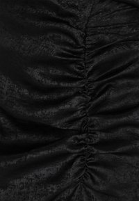 Tela negra con frunces recogidos, de textura suave, ligeramente brillante y con un brillo sutil, que crea un patrón ondulado en toda la superficie.