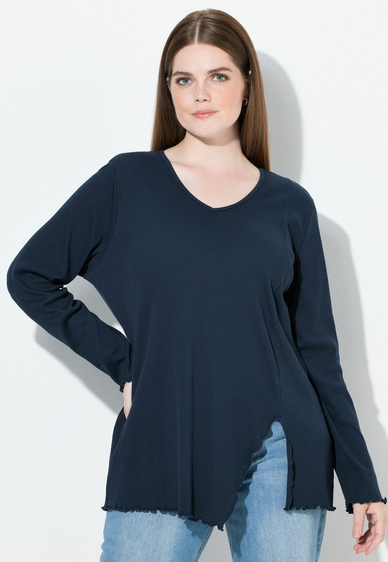 Top blu navy a maniche lunghe con scollo a V, caratterizzato da un orlo curvo con bordi frangiati e una vestibilità rilassata, realizzato in morbido tessuto a coste.