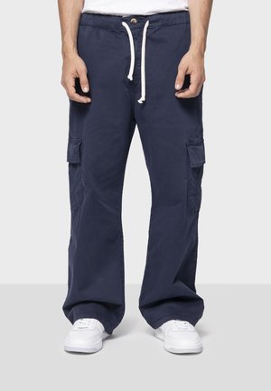 Pantaloni cargo navy cu o croială lejeră, talie elastică și șnur alb. Dispune de mai multe buzunare laterale și un material din bumbac durabil.