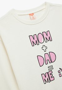 Sudadera color crema con cuello redondo que presenta un gráfico de texto en negro y rosa: "MAMÁ + PAPÁ = YO :)" en una fuente atrevida y juguetona.