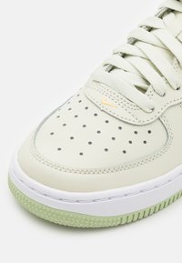 Zapatilla de cuero verde claro con caja de dedos perforada, mediasuela blanca y suela de goma verde pálido. Presenta cordones en tono a juego y detalle del logo en dorado.