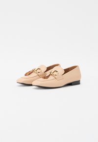 Beiga läderskor i loafermodell med spetsig tå och en liten svart klack, prydda med en dekorativ guldbuckle och fransar på framsidan.