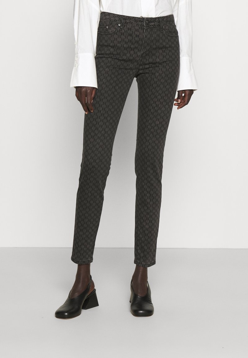 Pantalones de mezclilla en negro y gris con un patrón, de corte ajustado. Presentan bolsillo delantero y cremallera con cierre de botón.