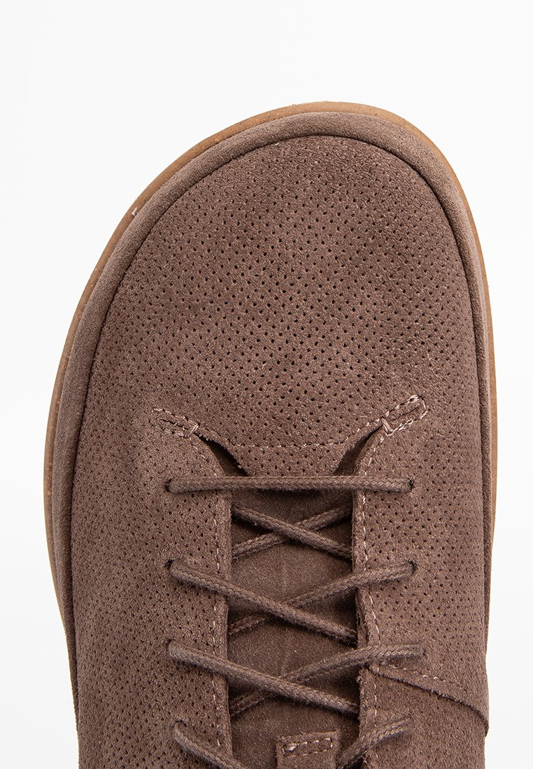 Braunes Wildleder-Schuhwerk mit einer durchbrochenen Textur, runder Zehenform und minimalistischer Schnürung. Verfügt über eine flexible Laufsohle für zusätzlichen Komfort.