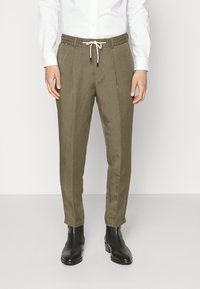 Olive green linen blend trousers with an elastic waistband and drawstring, featuring side pleats, tapered fit, and ankle-length cut.