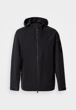 Jachetă neagră impermeabilă cu fermoar frontal, glugă reglabilă și manșete. Dispune de buzunare laterale și o etichetă cu logo pe mânecă.