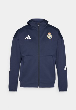 Navy zip-up jacket with a hood, features white Adidas logo and Real Madrid crest. Made of smooth fabric with side pockets.