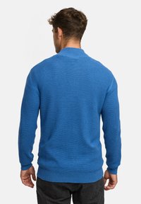 Blauer gestrickter Pullover mit langen Ärmeln, rundem Halsausschnitt und gerippten Bündchen. Strukturstoff mit einer taillierten Passform.