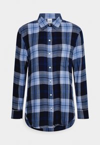 Blue and black plaid button-up shirt with long sleeves, featuring a collar, front pocket, and rounded hem. Made of a soft, woven material.