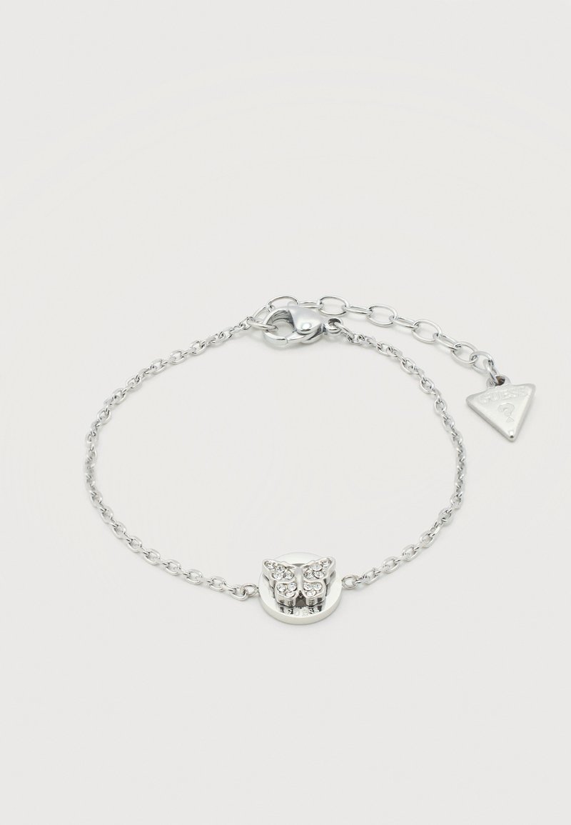 Bracelet en chaîne argentée avec un pendentif papillon orné de petits cristaux clairs et un fermoir ajustable avec une étiquette triangulaire.