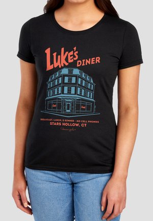 Woman wearing black T-shirt with "Luke's Diner" building illustration and text referencing Stars Hollow, CT and Gilmore Girls.