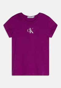 Fialové bavlněné tričko s krátkými ruk�ávy, s bílým a zeleným logem "CK" na prsou. Klasický kulatý výstřih, měkká textura.