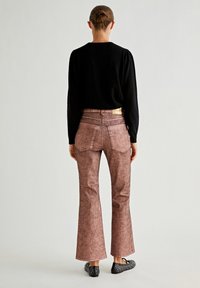 Udbredte jeans i et struktureret, lyst brunt materiale med høj talje og baglommer, parret med en sort langærmet top.