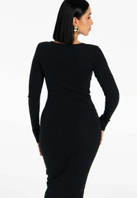 Czarna, prążkowana sukienka z długimi rękawami i dopasowanym krojem, z okrągłym dekoltem i gładką fakturą, podkreślająca kształt ciała.