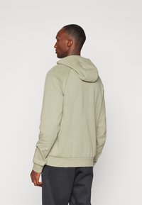 Hoodie vert olive clair avec capuche à cordon, poignets et ourlet côtelés. Fabriqué à partir d'un tissu doux, il présente une coupe décontractée et un design minimal.