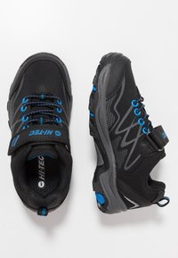 Schwarze Sportschuhe mit blauen Akzenten, ausgestattet mit einem Obermaterial aus Mesh, Gummisohle, verstellbarem Riemen und strukturierten Details an den Seiten.