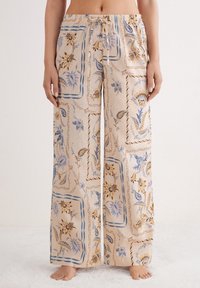 Pantaloni palazzo leggeri e fantasia in beige con motivi floreali blu e marroni, dotati di una vita elastica e di una vestibilità ampia.