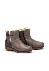 Bottes chelsea marron avec doublure en fausse fourrure, fermeture éclair sur le côté, couture décorative et semelle en caoutchouc imprimée. Fabriquées en cuir et en textile.