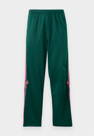Grønne sportsbukser i løs pasform med rosa side-striber og et Adidas-logo på underbenet. Blød tekstur, elastisk talje. 