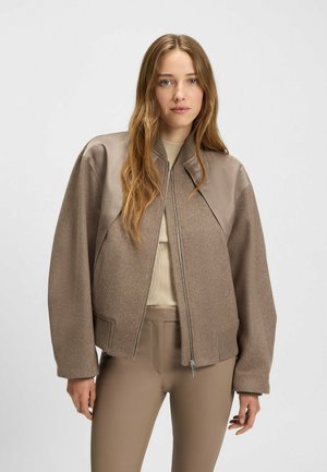 Bruine bomberjack met beige leren accenten, geribde manchetten en een rits aan de voorkant. Gemaakt van zachte stof met een gladde textuur en een relaxte pasvorm.