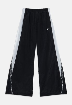 Pantalones negros de pierna ancha con cintura ajustable con cordón, paneles laterales de malla y logo blanco de Nike en el frente, con branding a lo largo del lateral.
