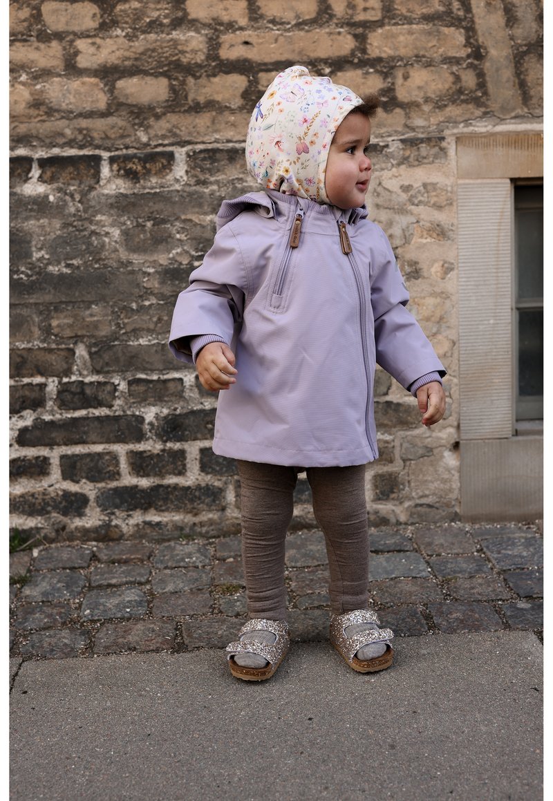Manteau imperméable lilas avec capuche, leggings marron et sandales scintillantes. Comprend des boutons en bois et une doublure de capuche à motif floral.