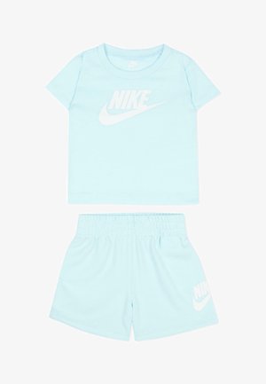 Completo sportivo Nike per bambini azzurro chiaro con maniche corte, maglia girocollo, pantaloncini con vita elastica e logo Nike bianco sopra e sotto.