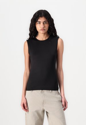 Black sleeveless top made of stretchy fabric with a round neckline. Fitted design, smooth texture, paired with beige trousers.