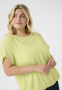 Løsre gerne limegrøn bluse lavet af letvægtsstof, med rund hals og korte ærmer; subtil tekstur og svævende design.