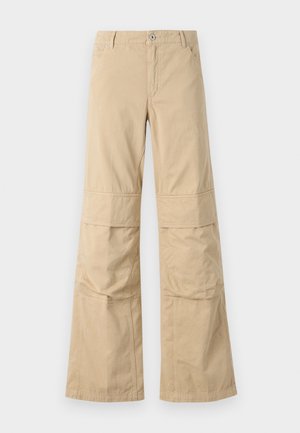 Beige, laza szabású, pamut anyagú, bő szárú nadrág, látható varrással, elülső zsebekkel és gombos záródással.