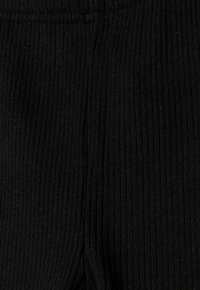 Legging noirs côtelés avec un tissu texturé et une taille élastique. Le matériau semble doux avec des rayures horizontales visibles.