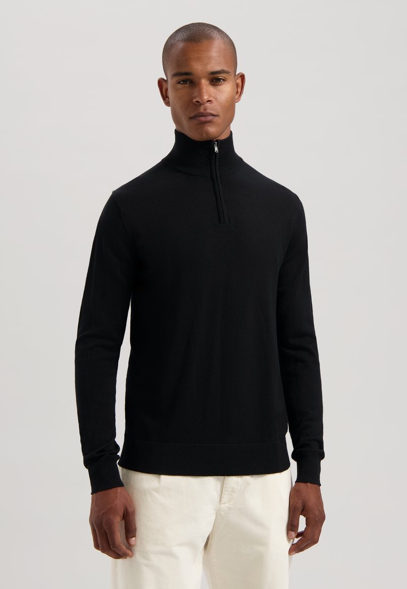 Maglione nero con zip, colletto alto, maniche lunghe e polsini a coste. Realizzato in tessuto morbido, presenta una silhouette aderente e linee pulite.