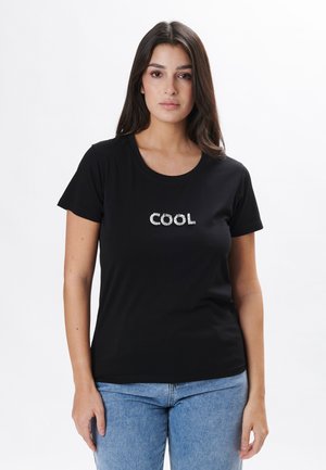 Camiseta de algodón negra con mangas cortas, que presenta la palabra "COOL" en letras plateadas metálicas en el pecho. Ajuste casual.