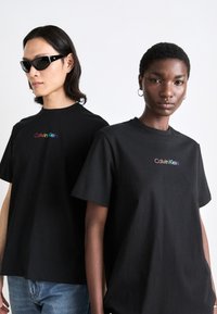 Juodos medvilninės marškinėliai trumpomis rankovėmis, su daugiaspalviu "Calvin Klein" logotipu ant krūtinės. Tekstūruota medžiaga su laisvu siluetu.