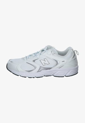 Scarpe da ginnastica bianche con tomaia in rete, dettagli argentati e suola ammortizzata. Presentano lacci e una piccola linguetta sul tallone per facilitare l'indossamento.