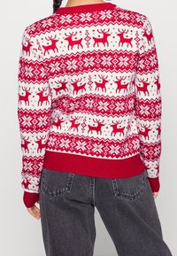 Roter und weißer Strickpullover mit einem festlichen Muster aus Rentieren und Schneeflocken, mit gerippten Bündchen und Saum sowie einem Rundhalsausschnitt.