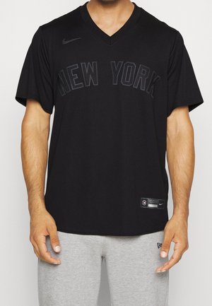 Musta Nike v-paita, jossa on kohotettu "NEW YORK" -painatus. Lyhyt hiha, kevyttä kangasta, pieni logo vasemmassa olkapäässä.