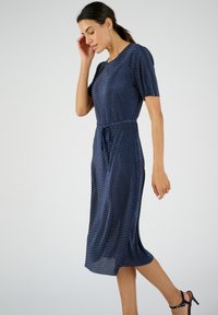 Vestido azul marino con puntos, con escote redondo, mangas cortas, cintura elástica y detalle de lazo, con longitud midi y tejido ligero.