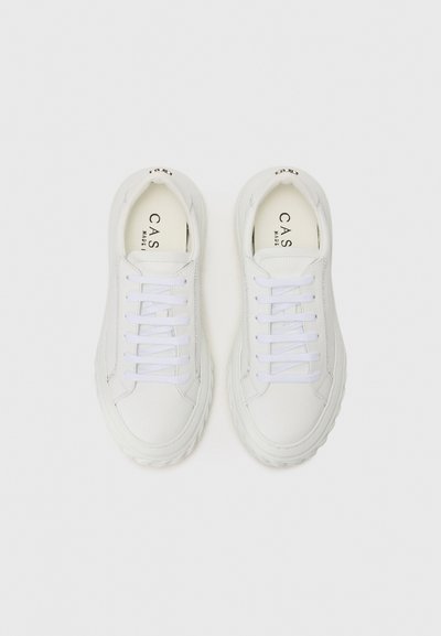 Vita sneakers med en slät läderexteriör, tjock gummisula och vita snören. Har en subtil logotyp på tungan.