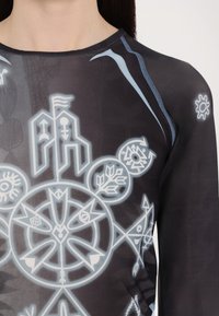 Black sheer long-sleeve top featuring intricate white and light blue graphic patterns, including symbols and geometric shapes.
