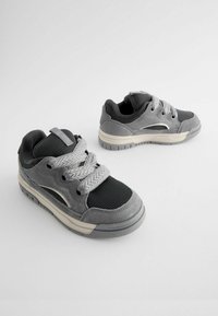Grå sneakers med en kombination af ruskind og mesh-materialer, teksturerede snørebånd og en gummisål med et lavprofil design.